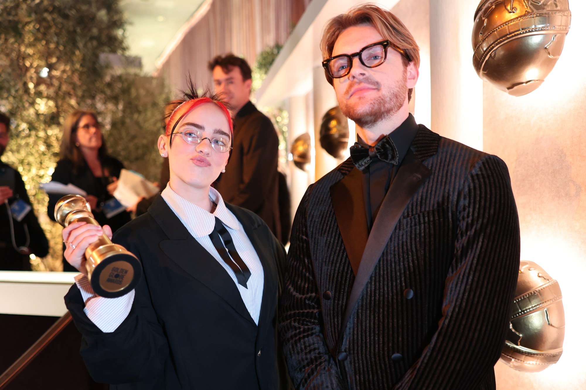 Billie Eilish and FINNEAS beam while holding their Golden Globe for